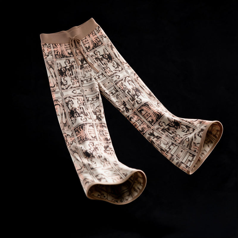 Wide leg jacquard knit trousers in a figural medieval pattern of cream, black and coral, shown in flat drape