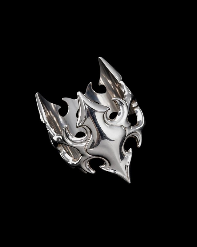 Sculptural silver flame shaped ring with open spikes and crescent cutouts, angled view