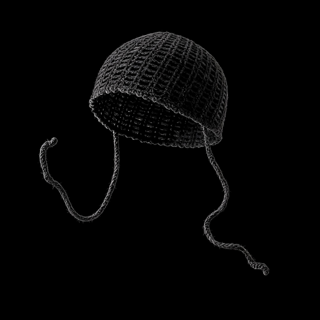 Black open mesh crochet cap with long braided ties on dark ground