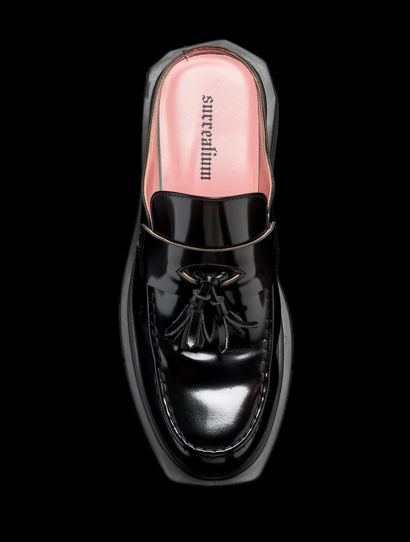 Top view of a glossy black tassel loafer mule with pink lining on a chunky black lugged sole