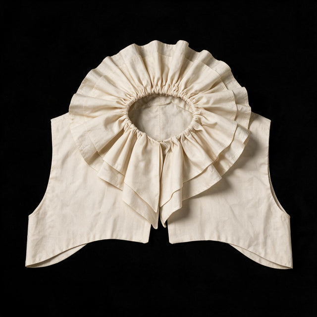 Ecru ruff collar laid flat, gathered frill circling the neck above a pointed yoke