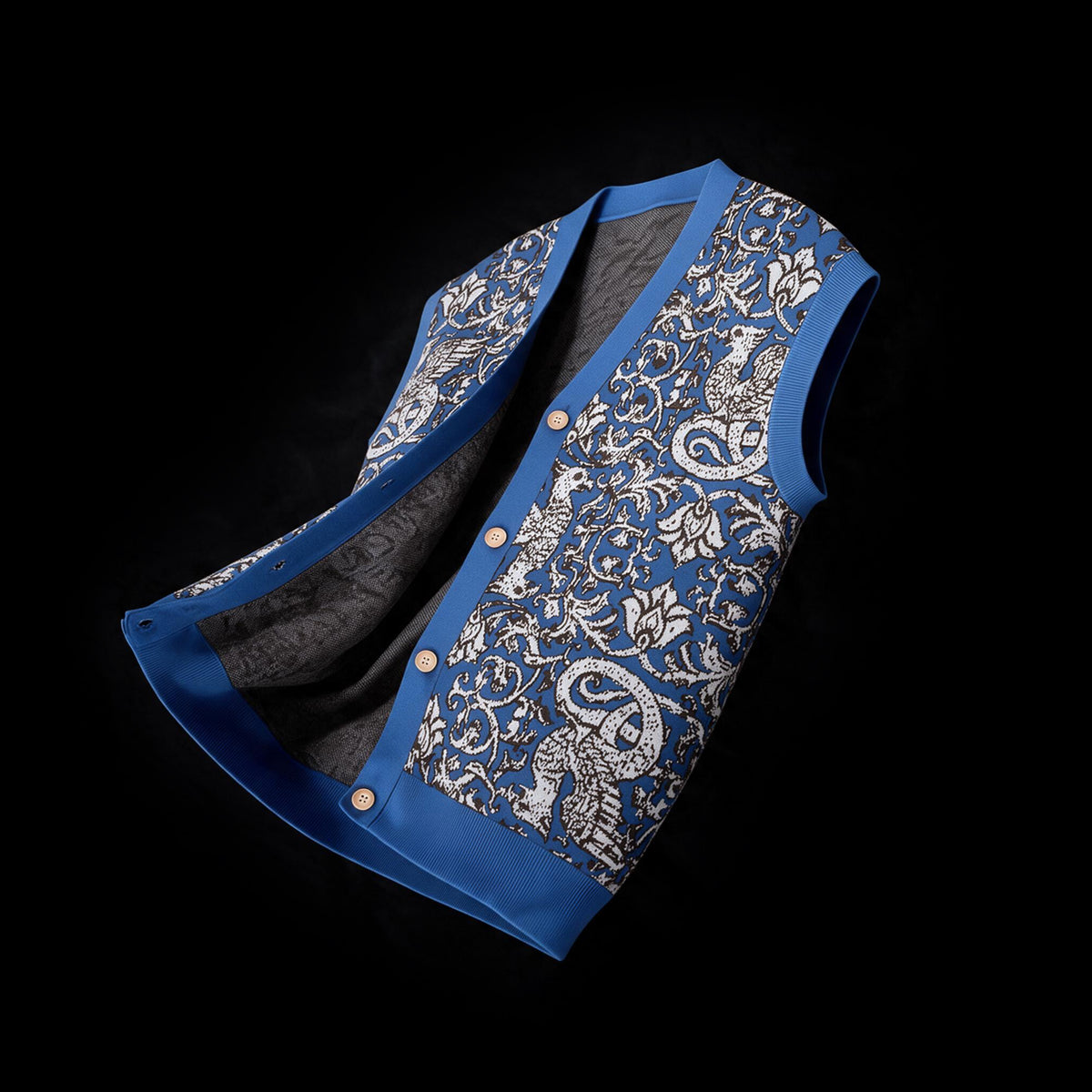 Blue and white jacquard knit sweater vest with foliate motif, ribbed V neck and button placket, on black