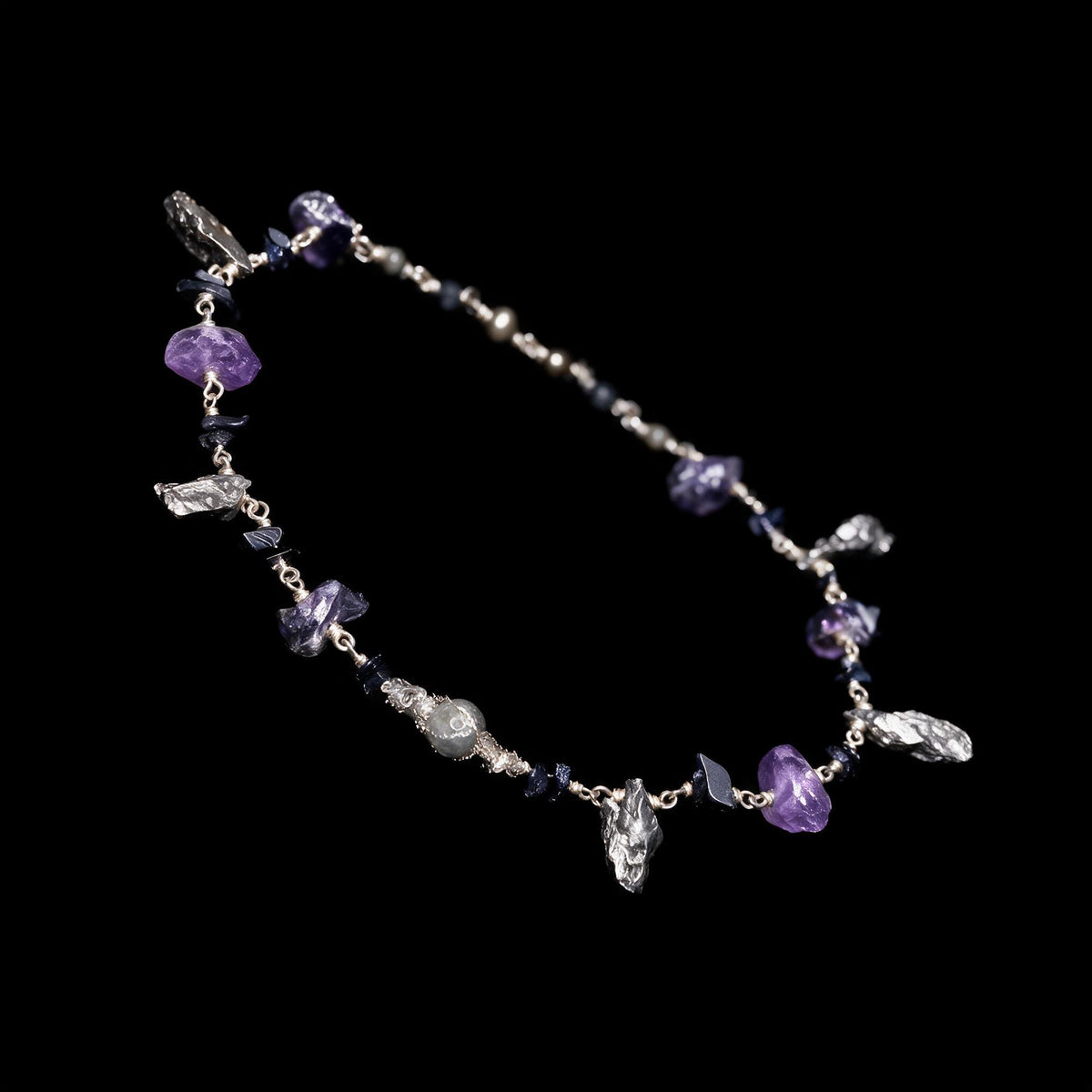 Sterling silver necklace with meteorite fragments, raw amethyst and dark stones on a black ground